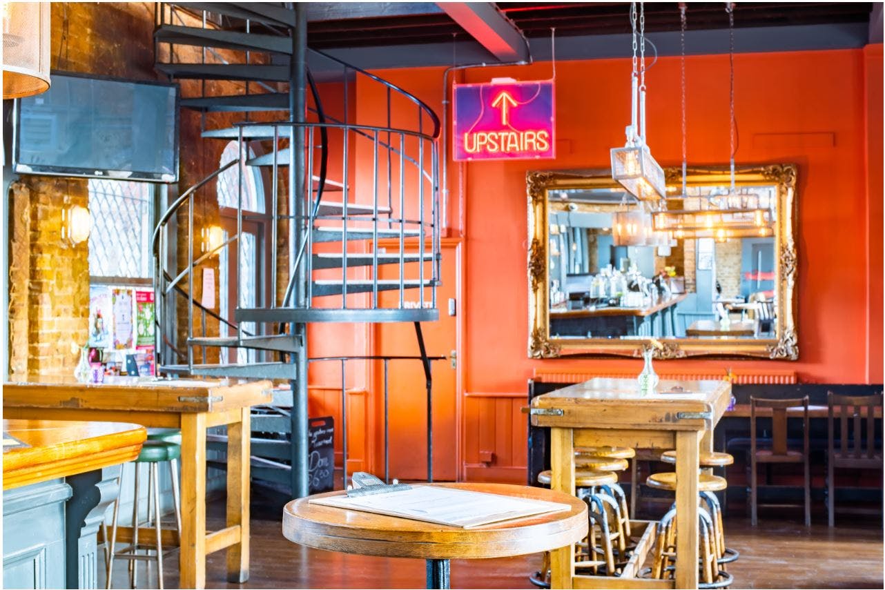 Vibrant event space with spiral staircase, ideal for networking and receptions in Denmark Hill.