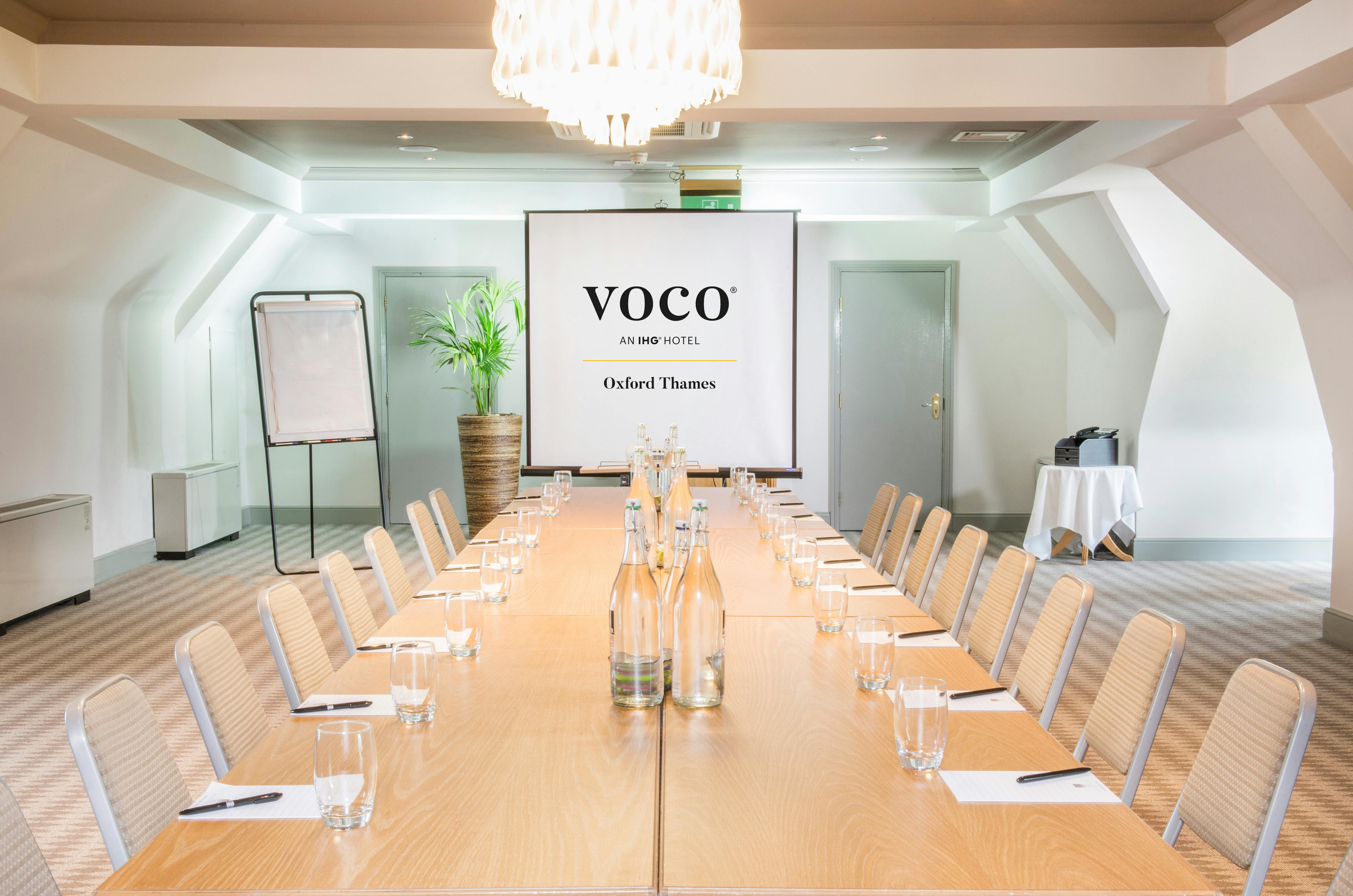 Corporate meeting room at voco™ Oxford Thames Hotel with bright ambiance and branding.