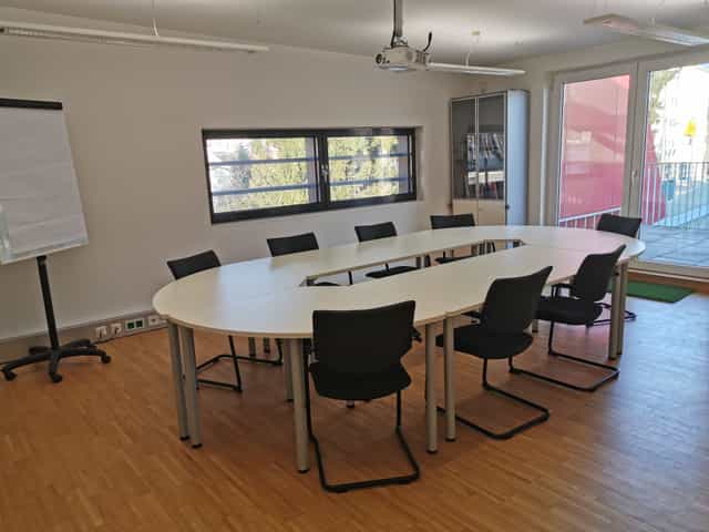 Modern meeting room with oval table at JUFA Hotel Graz-Süd for workshops and brainstorming.