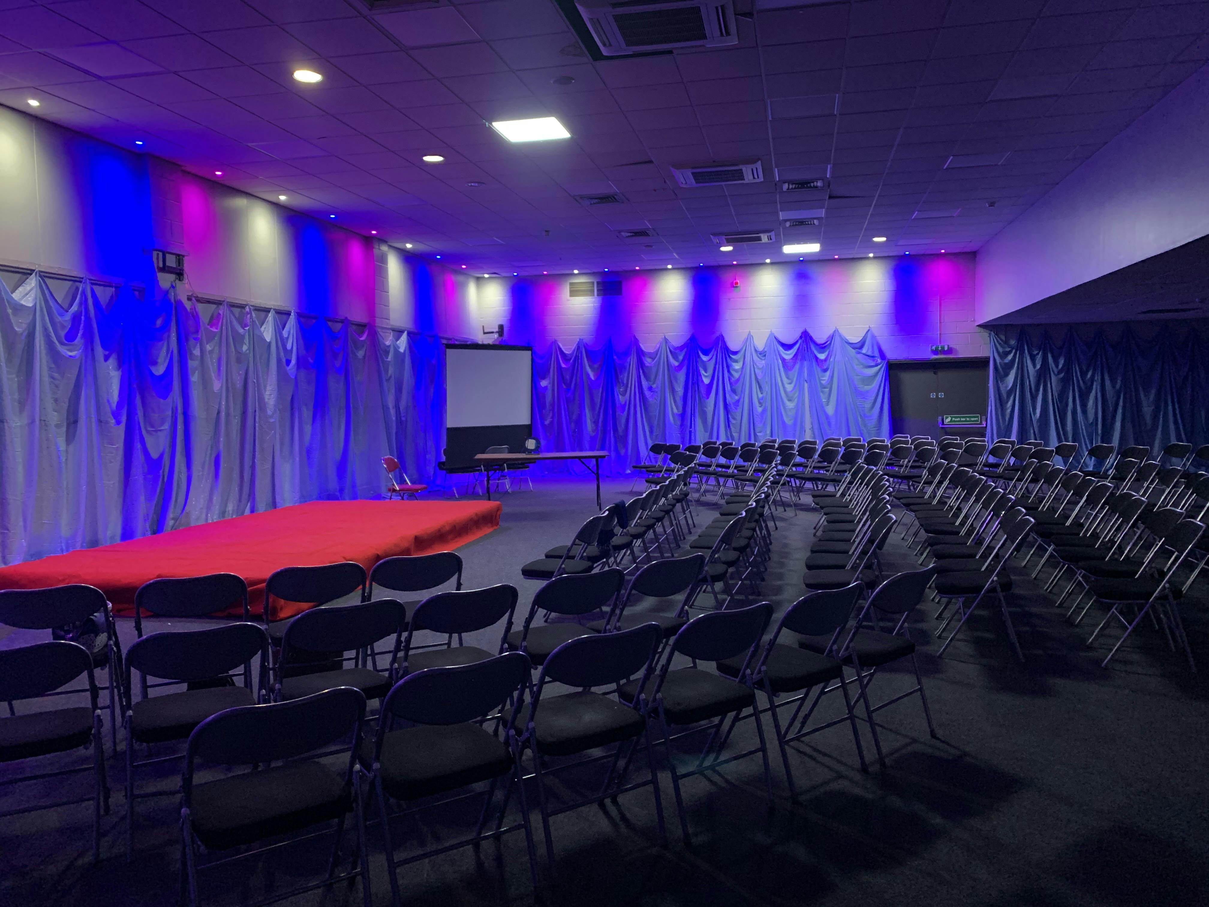 Versatile Masefield Suite venue with red stage, ideal for conferences and performances.