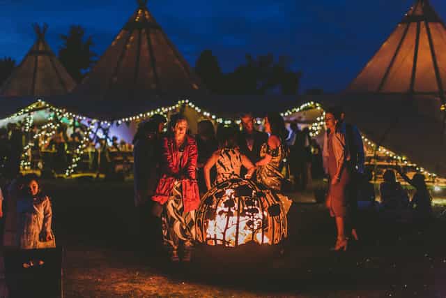 Vibrant outdoor event venue with illuminated tents and cozy fire pit in Vanstone Park.