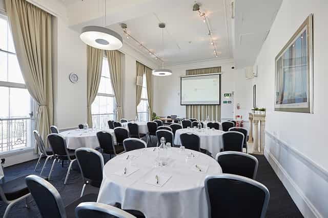 Corporate meeting room with round tables, ideal for workshops and presentations.