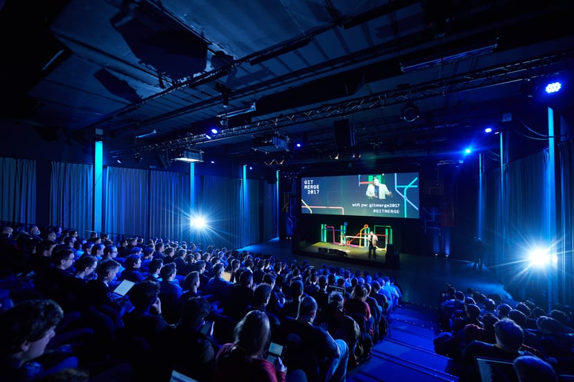 Engaged audience at The Egg Brussels conference with dynamic stage lighting.