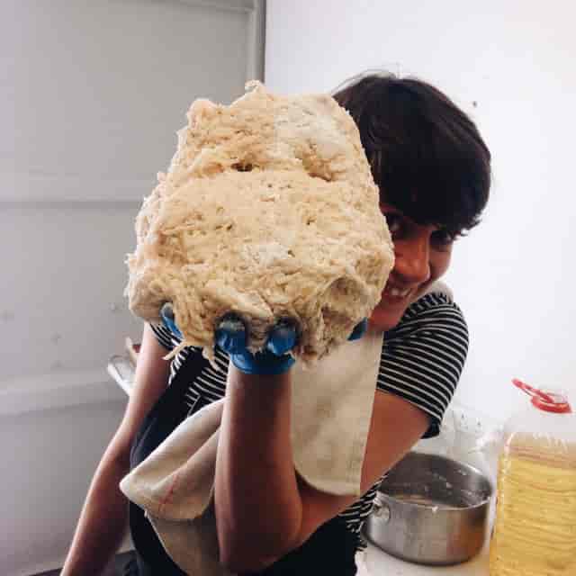 Person holding large dough at Yurt Cafe, St Katharine's Precinct, culinary workshop event.