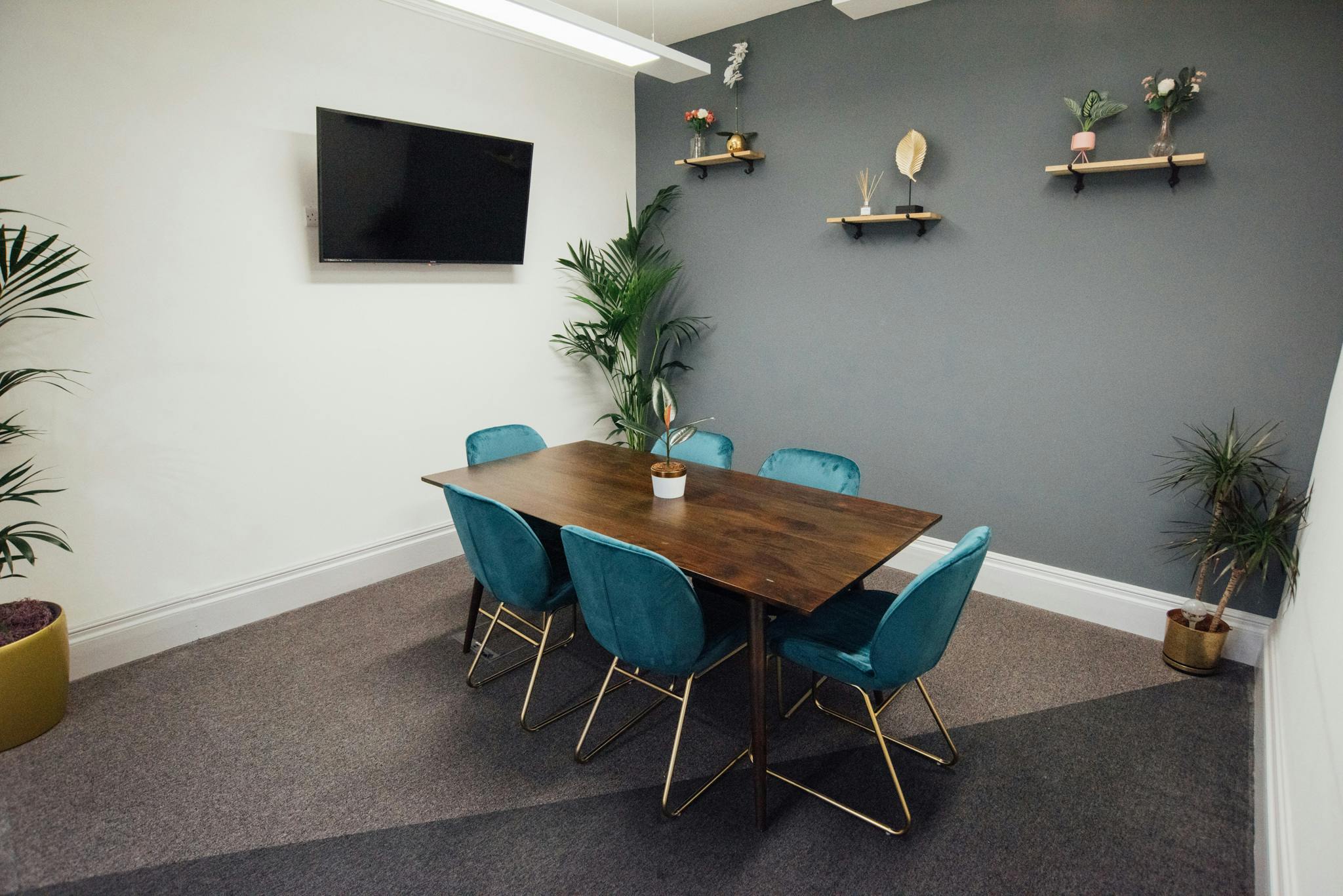 Modern meeting room in Wizu Workspace with wooden table and teal chairs for events.