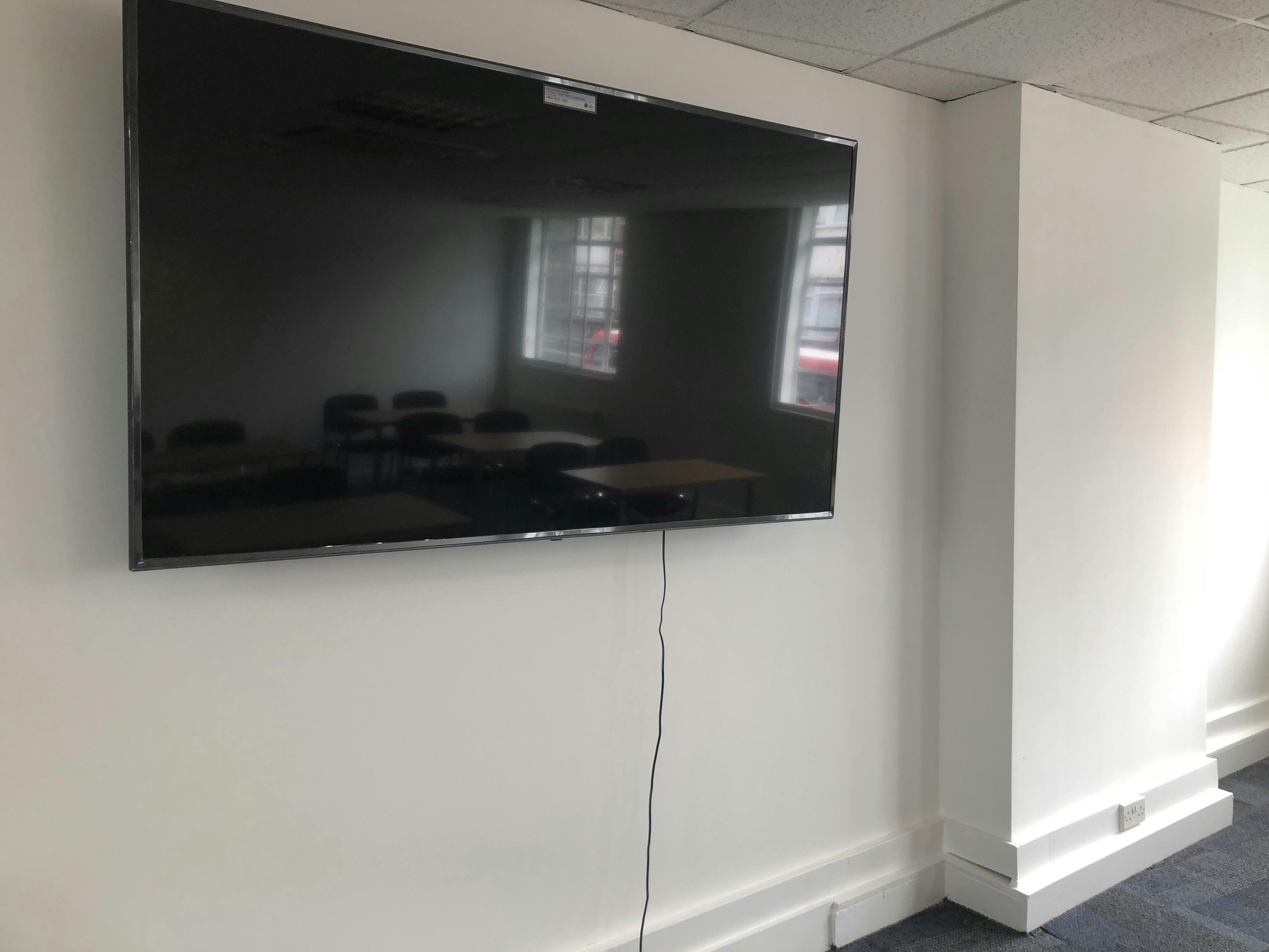 Modern seminar room with wall-mounted TV, ideal for presentations and video conferencing.