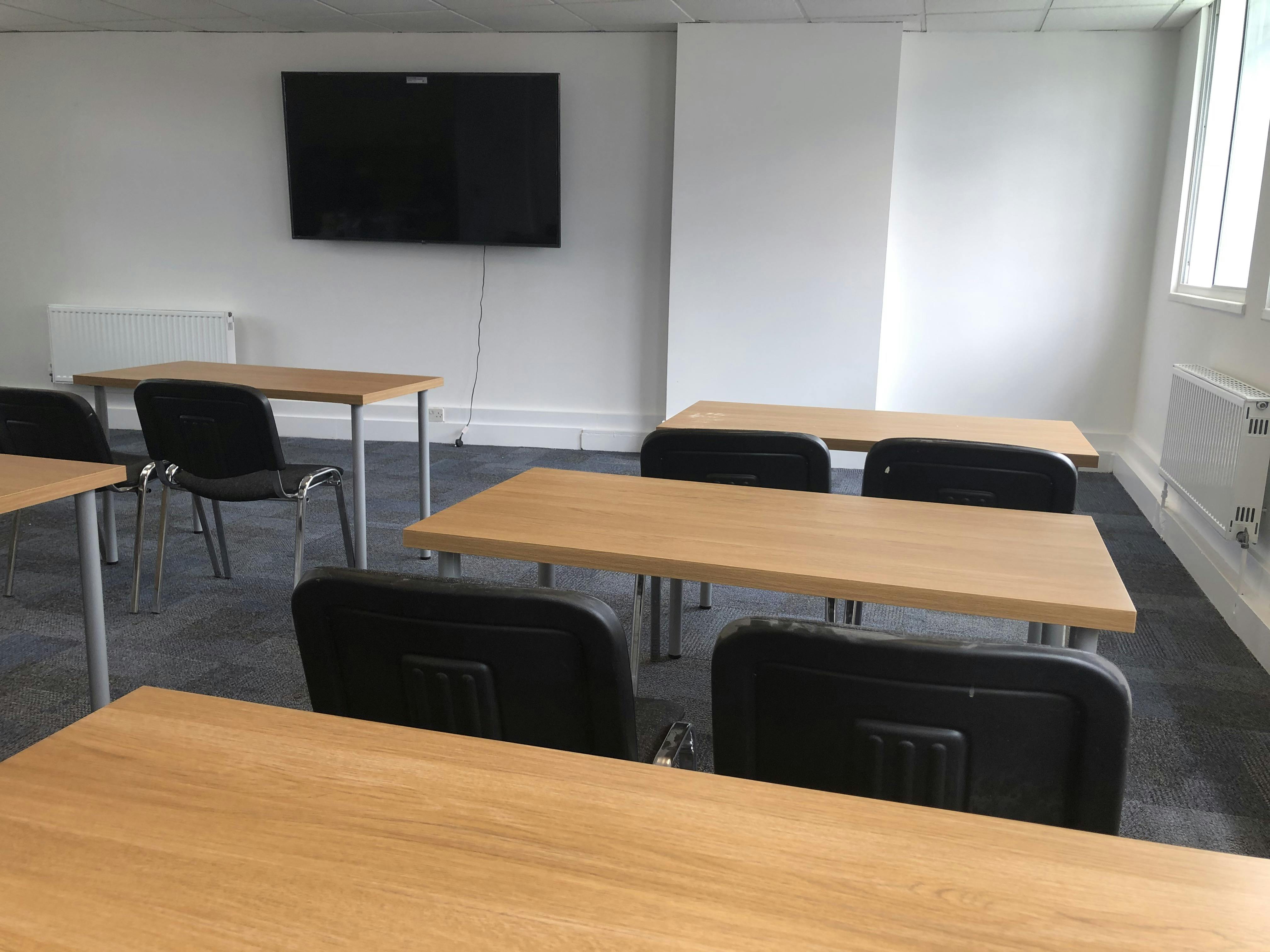 Minimalist classroom setup with wooden tables for leadership seminars and training sessions.