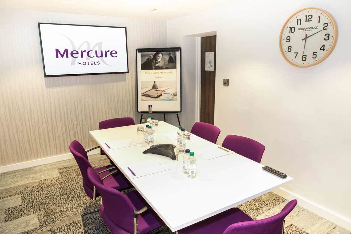 Modern Sussex Suite meeting room with white table and purple chairs at Mercure London Paddington.