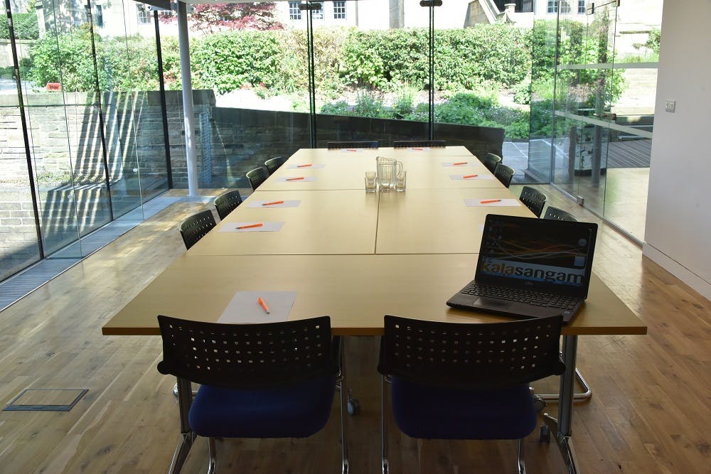 Modern glass meeting room with wooden table, ideal for corporate events and presentations.