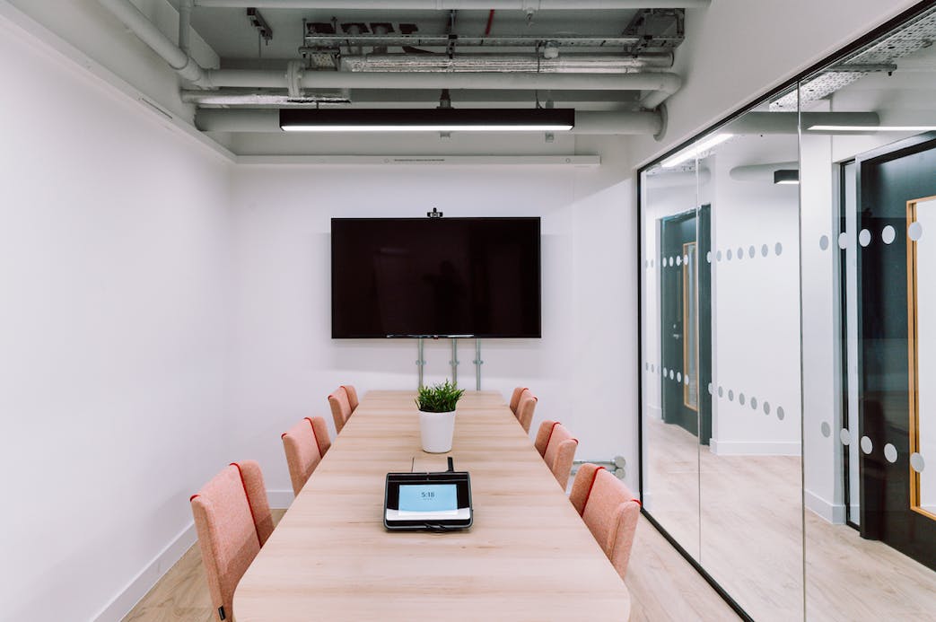 Modern Alto Meeting Room with wooden table, pink chairs for collaborative events.