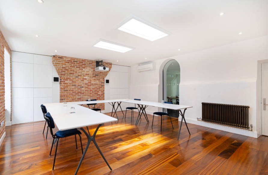 Modern meeting room with exposed brick, ideal for workshops and presentations. - Banner