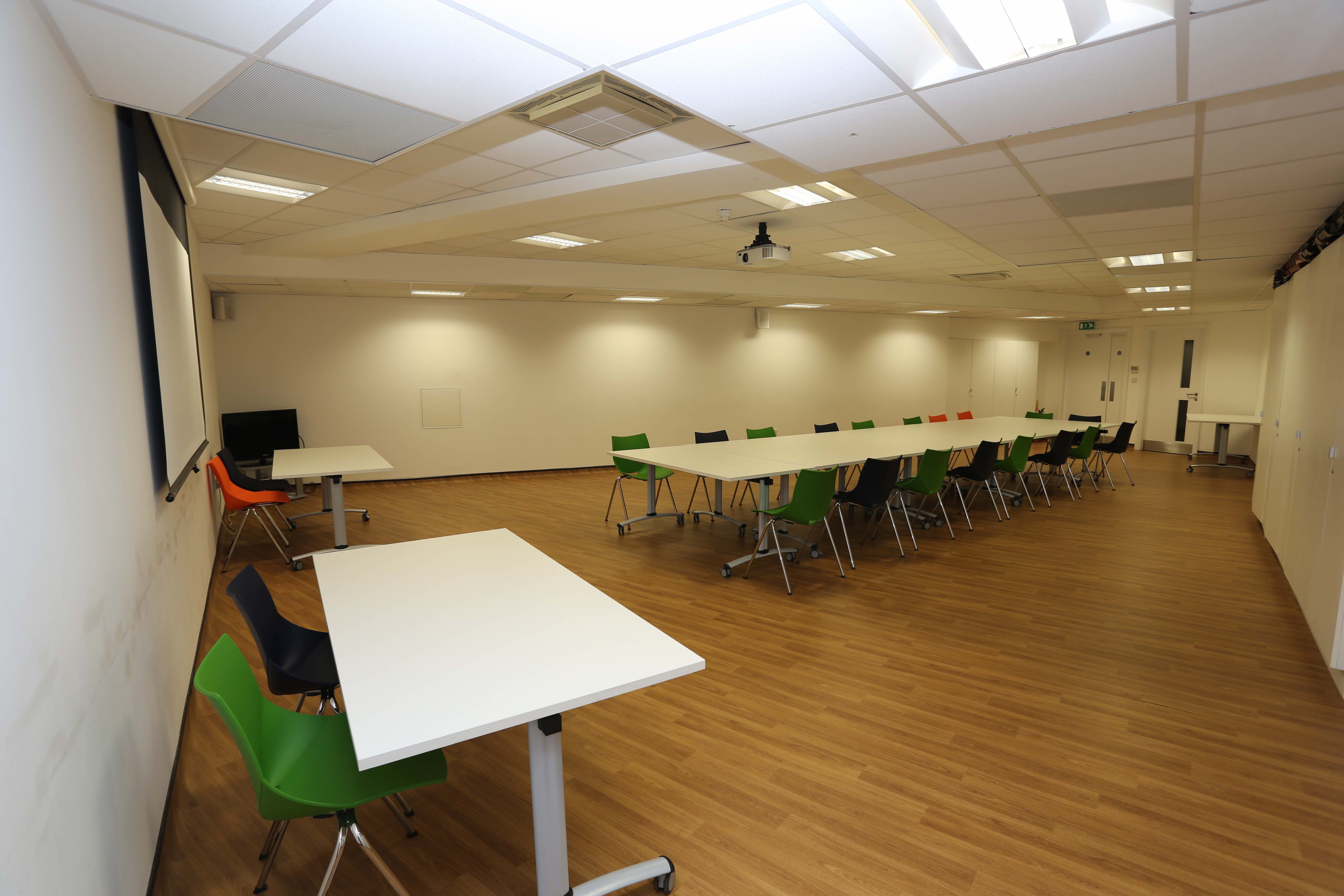 Main hall in Chinese Community Centre with colorful chairs, perfect for workshops and meetings. - Banner
