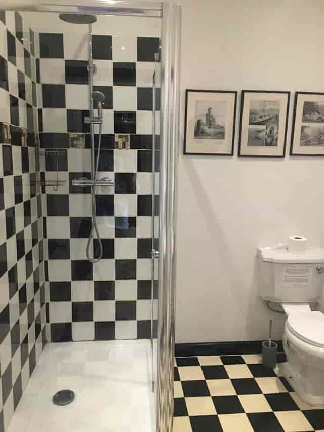 Stylish koa tree restroom with modern shower, vintage art, ideal for events.
