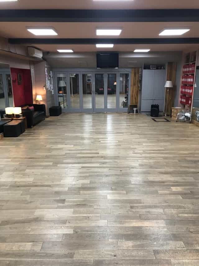 Spacious event venue with polished wooden floors, ideal for workshops and receptions.