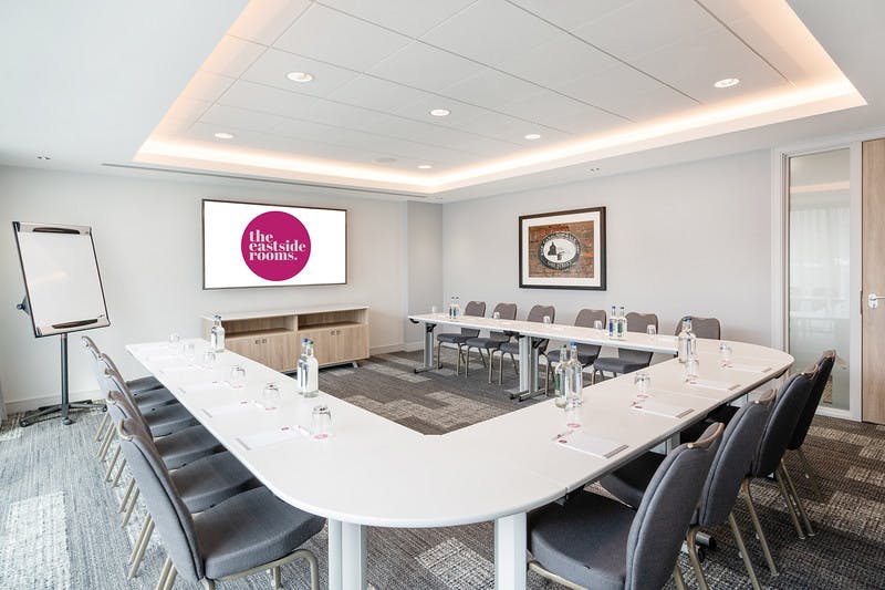 Modern meeting room with U-shaped table, ideal for workshops and strategic planning.