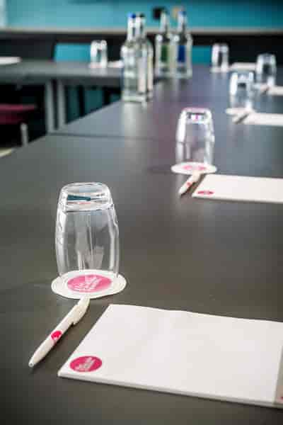 Meeting Room Two setup with glass tumblers, pens, and notepads for professional events.