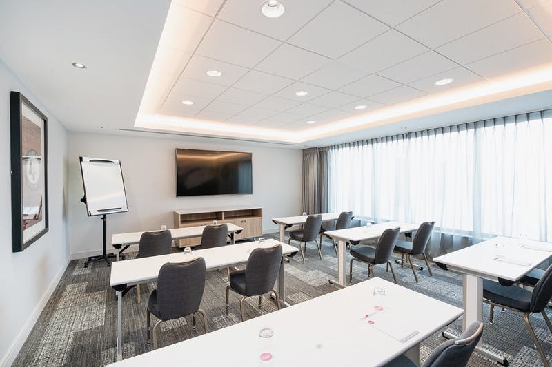 Modern Meeting Room Five with white tables and natural light for professional gatherings.