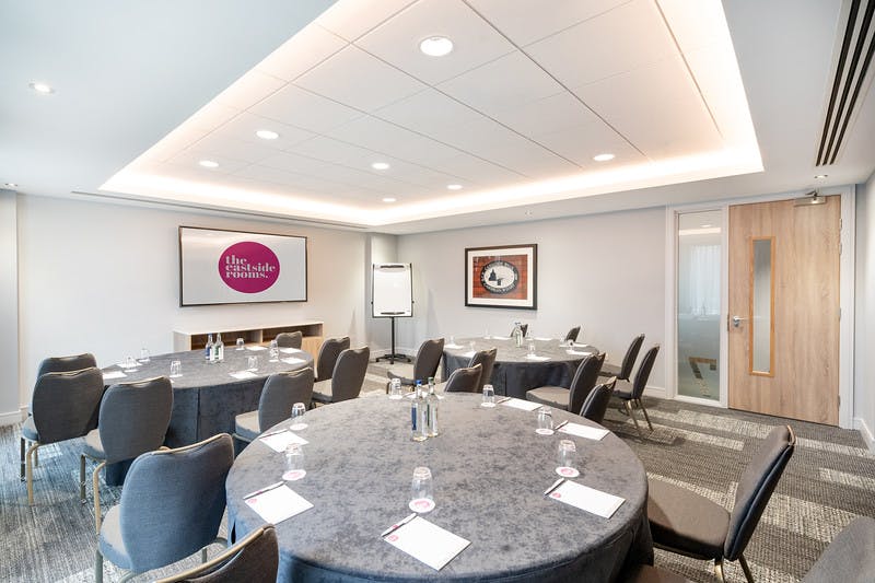 Meeting Room Seven at The Eastside Rooms, featuring circular tables for corporate meetings.