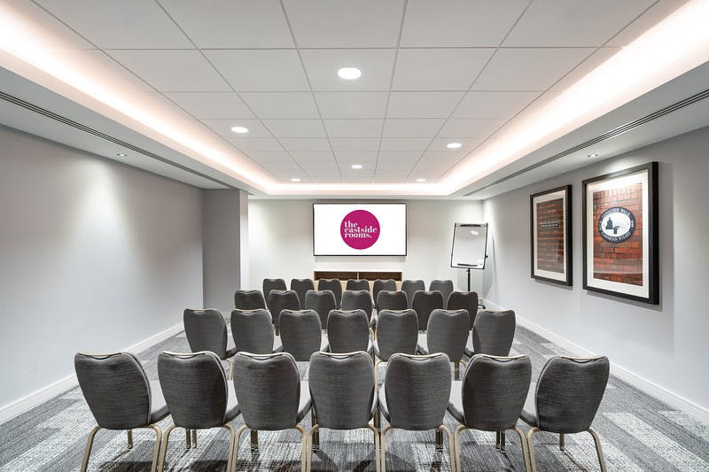 Modern meeting room with comfortable chairs and presentation screen for professional events.