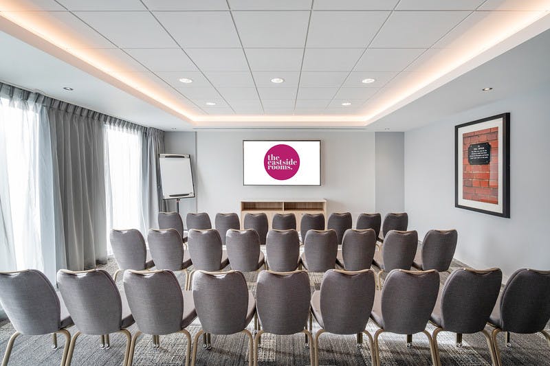 Meeting Room Eleven setup for corporate presentations with elegant chairs and large screen.