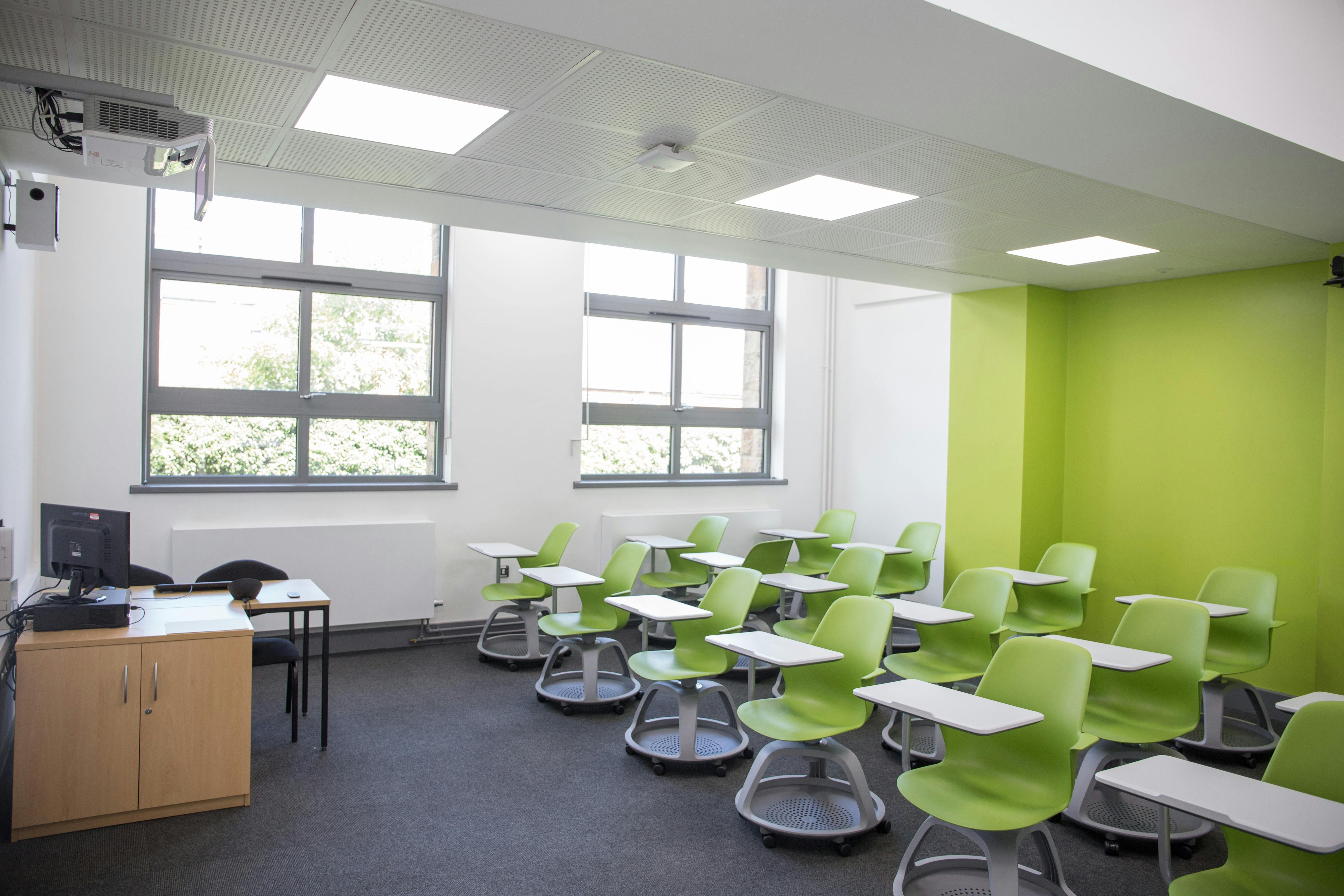 Modern classroom at Chesterfield College with green accent wall, ideal for workshops and meetings.