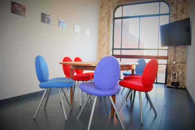 Modern meeting room with round table and colorful chairs for workshops and team meetings.