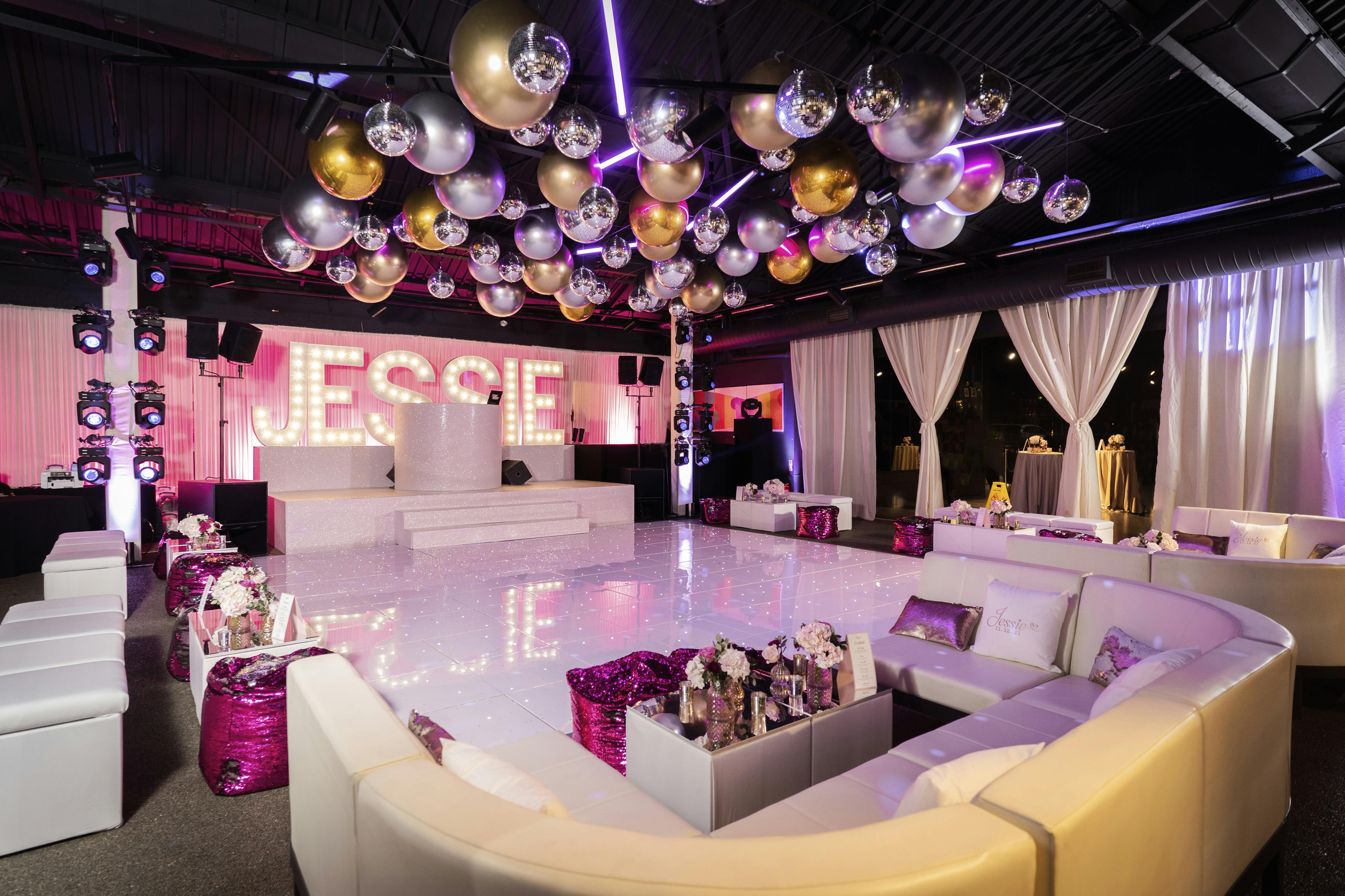 Vibrant event space at The Engine Rooms with elegant seating and "JESSIE" backdrop for celebrations.