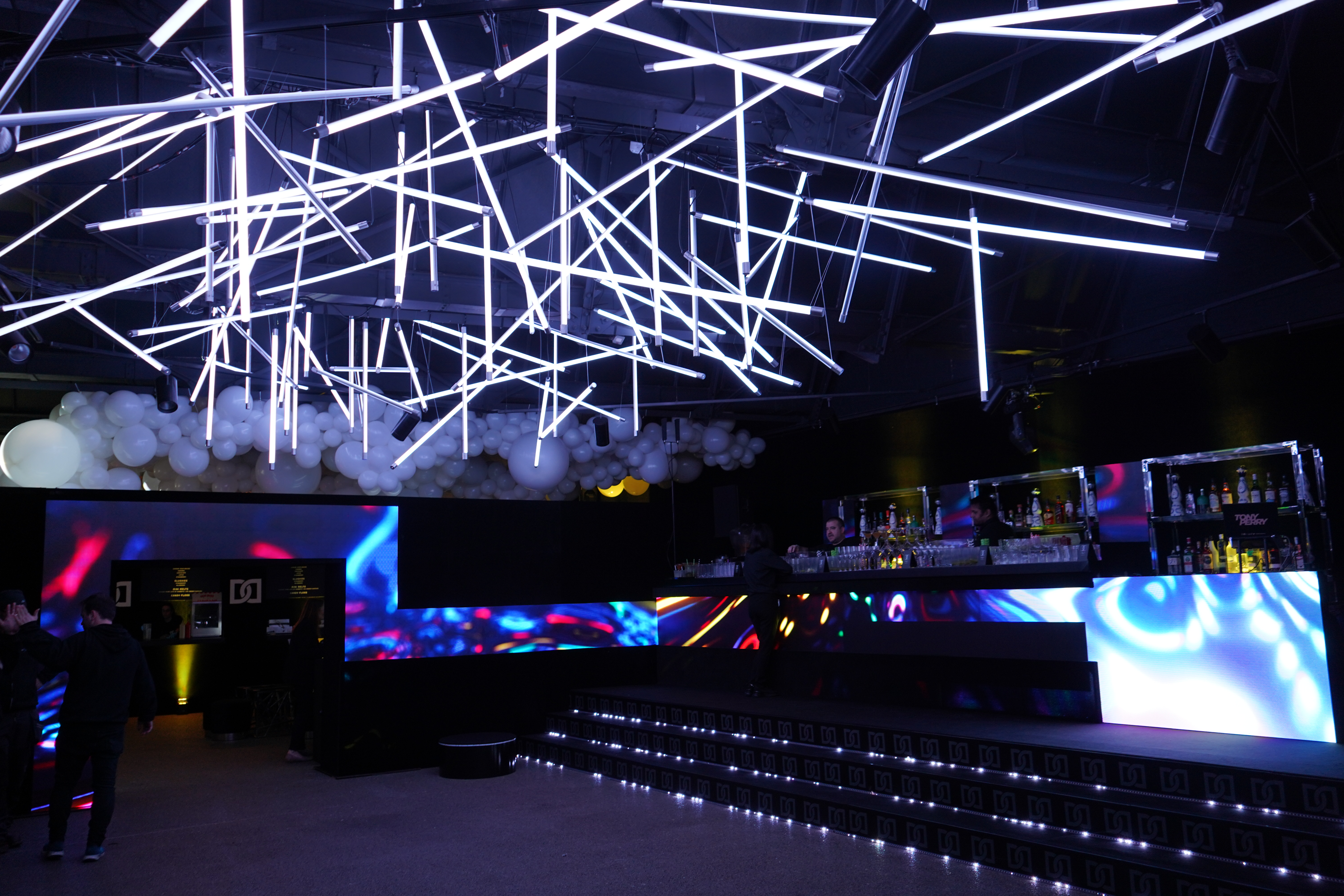 Modern event space with dynamic lighting and sleek bar, ideal for corporate gatherings. - Banner