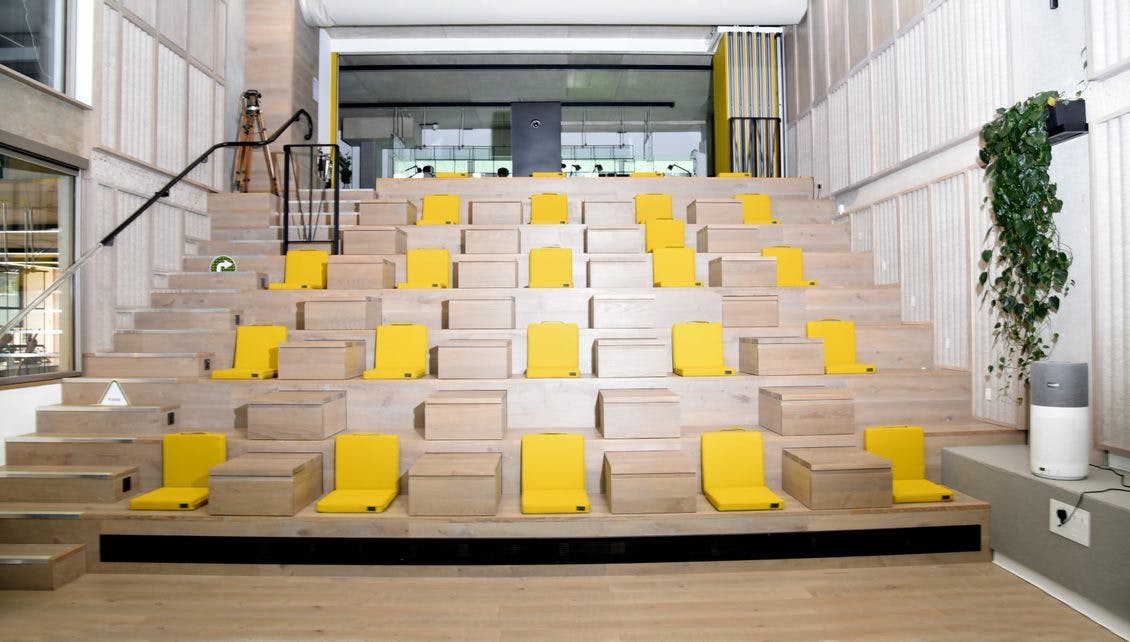 Modern amphitheater seating with yellow cushions for presentations and workshops at Storey Club.