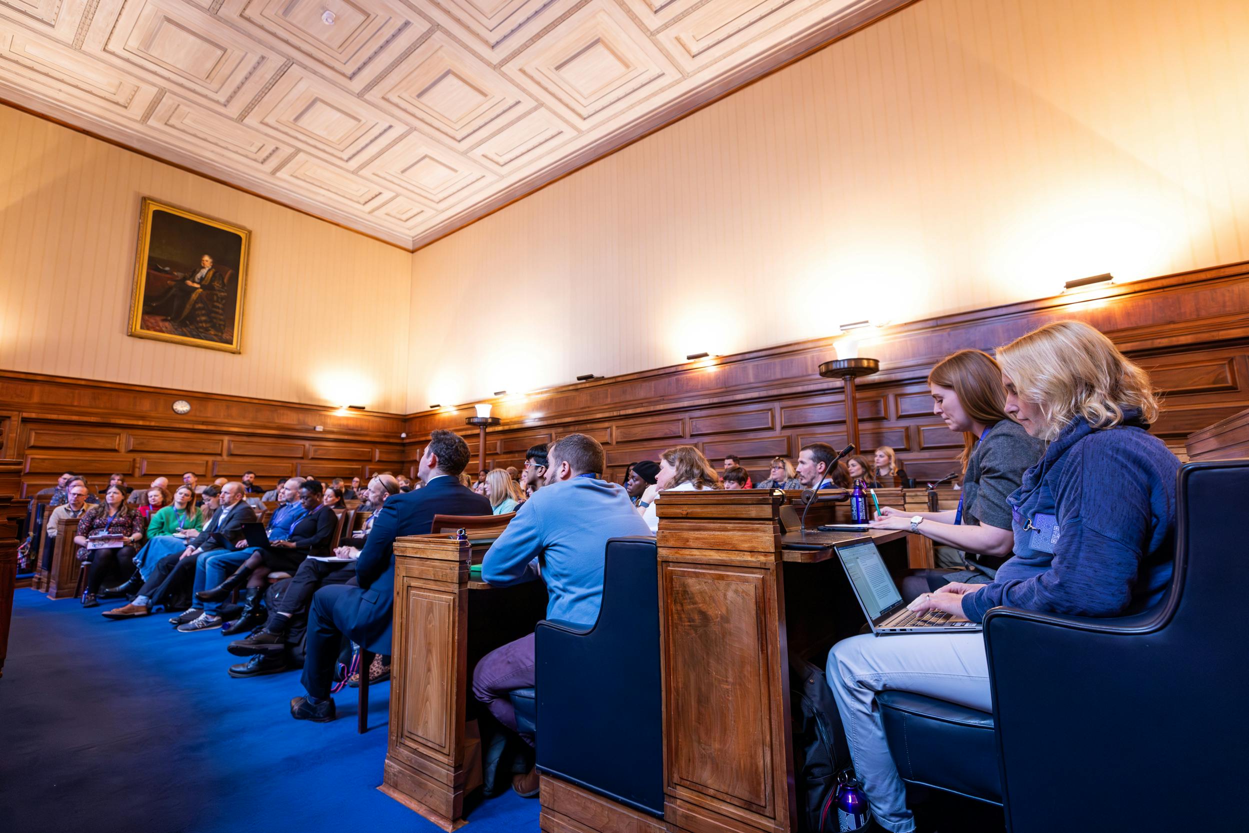 Engaged audience at a conference in the historic Senate Room, University of London.