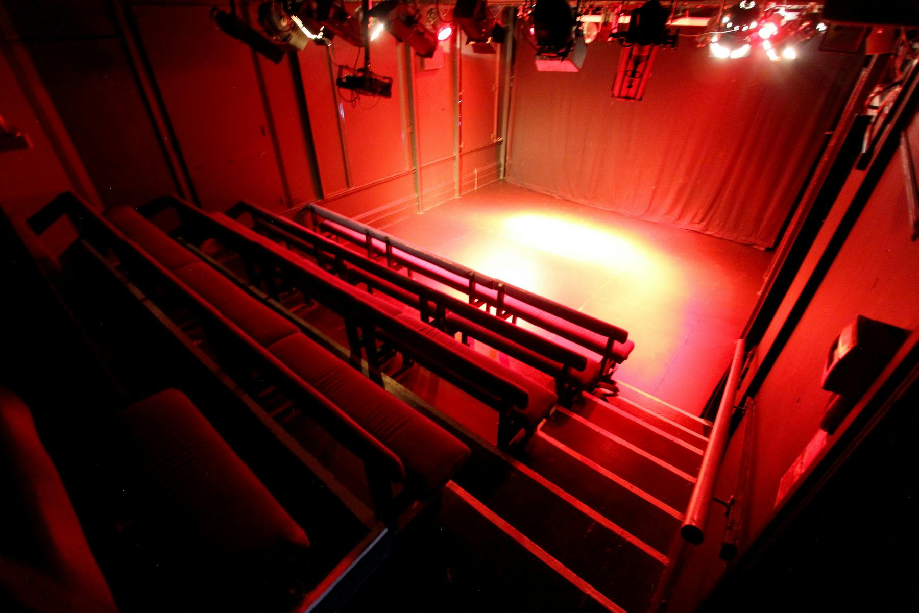 Black Box Theatre with tiered seating and red lighting for intimate events and performances.