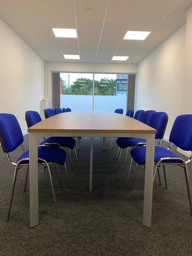 Modern meeting room with long table and blue chairs at Bridge School of Excellence.