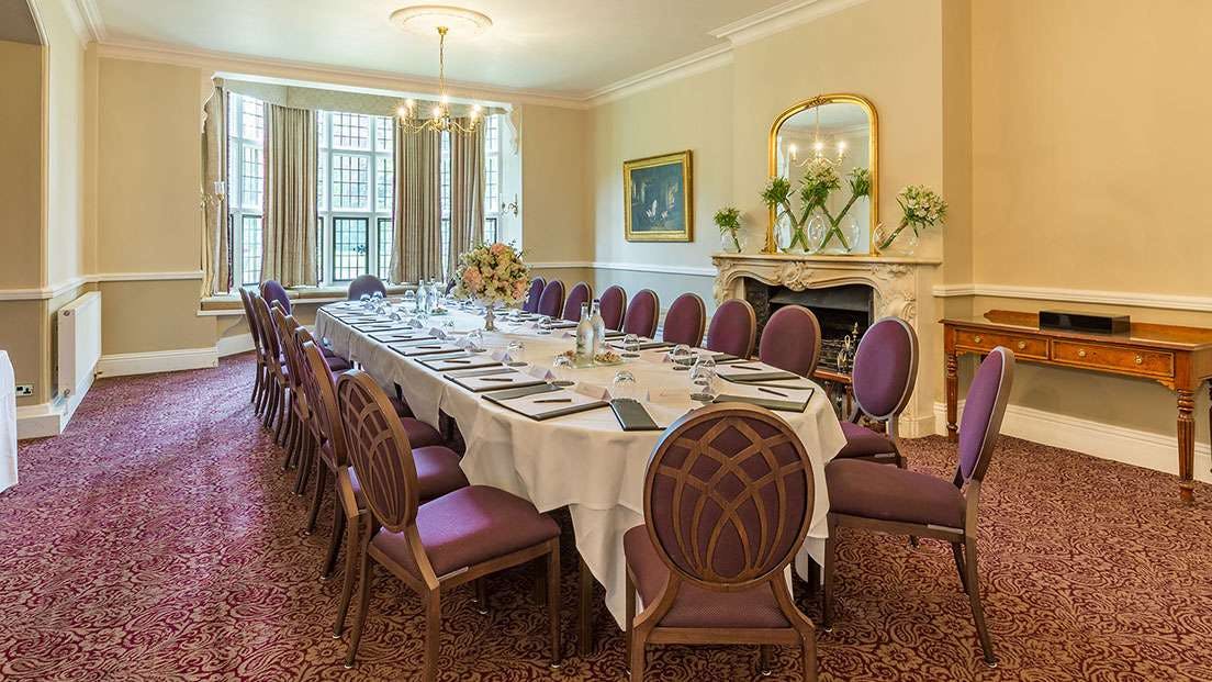 Elegant meeting room at Rhinefield House Hotel with plush purple chairs for corporate events.