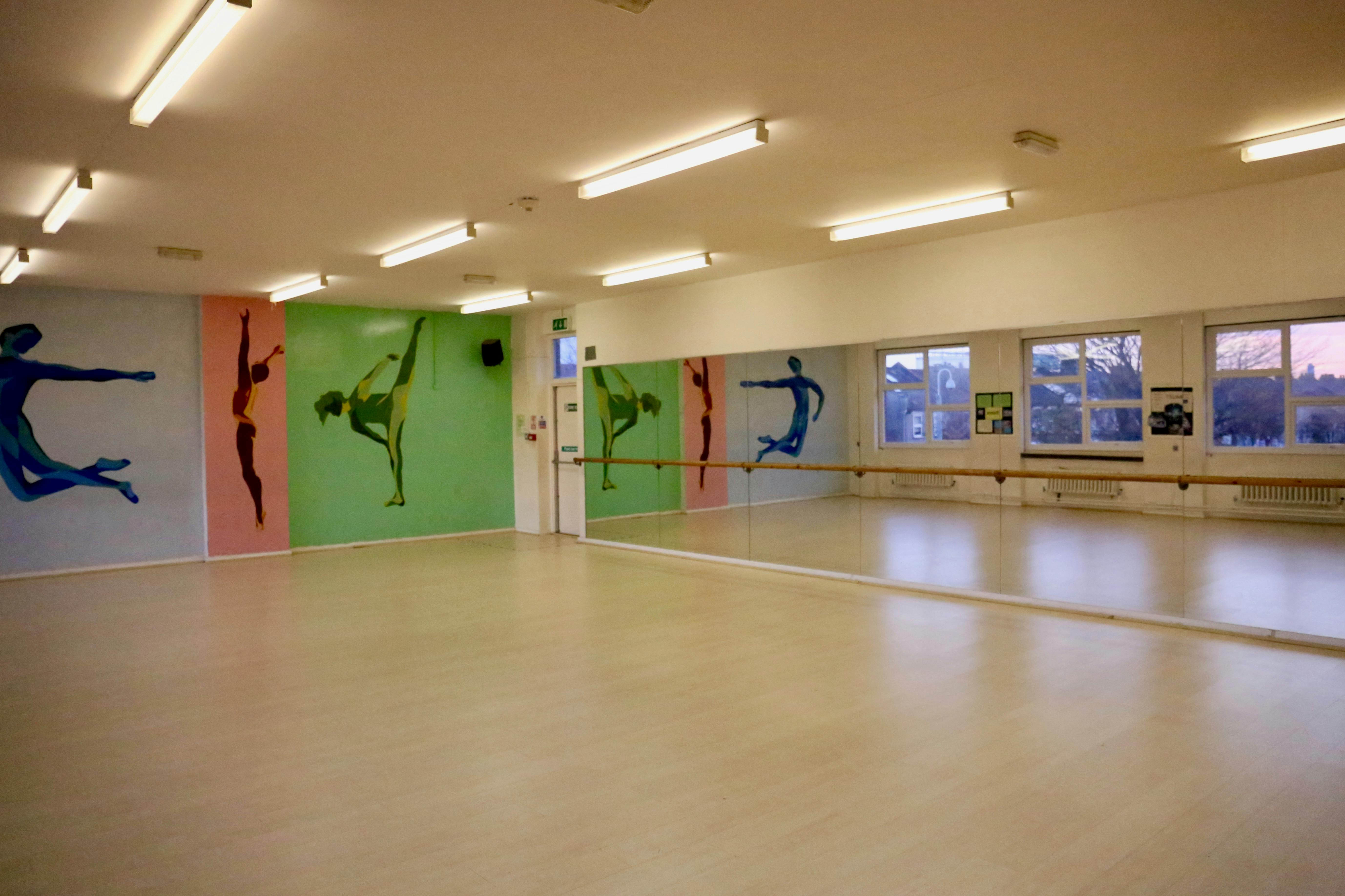 Spacious dance studio with vibrant murals, ideal for classes and workshops.