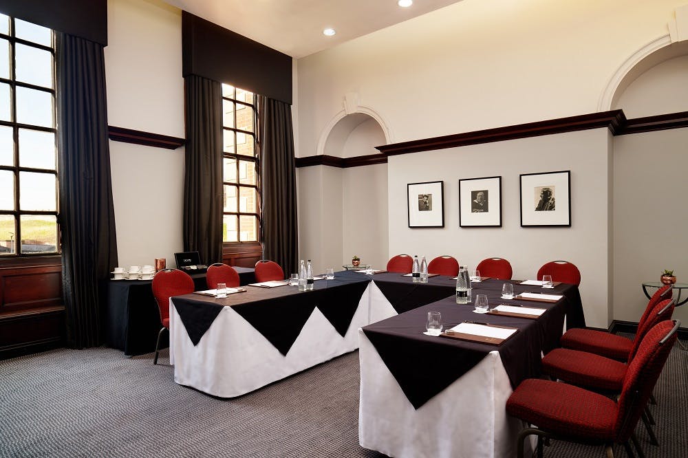 Elegant meeting room with U-shaped table, natural light, ideal for professional events.