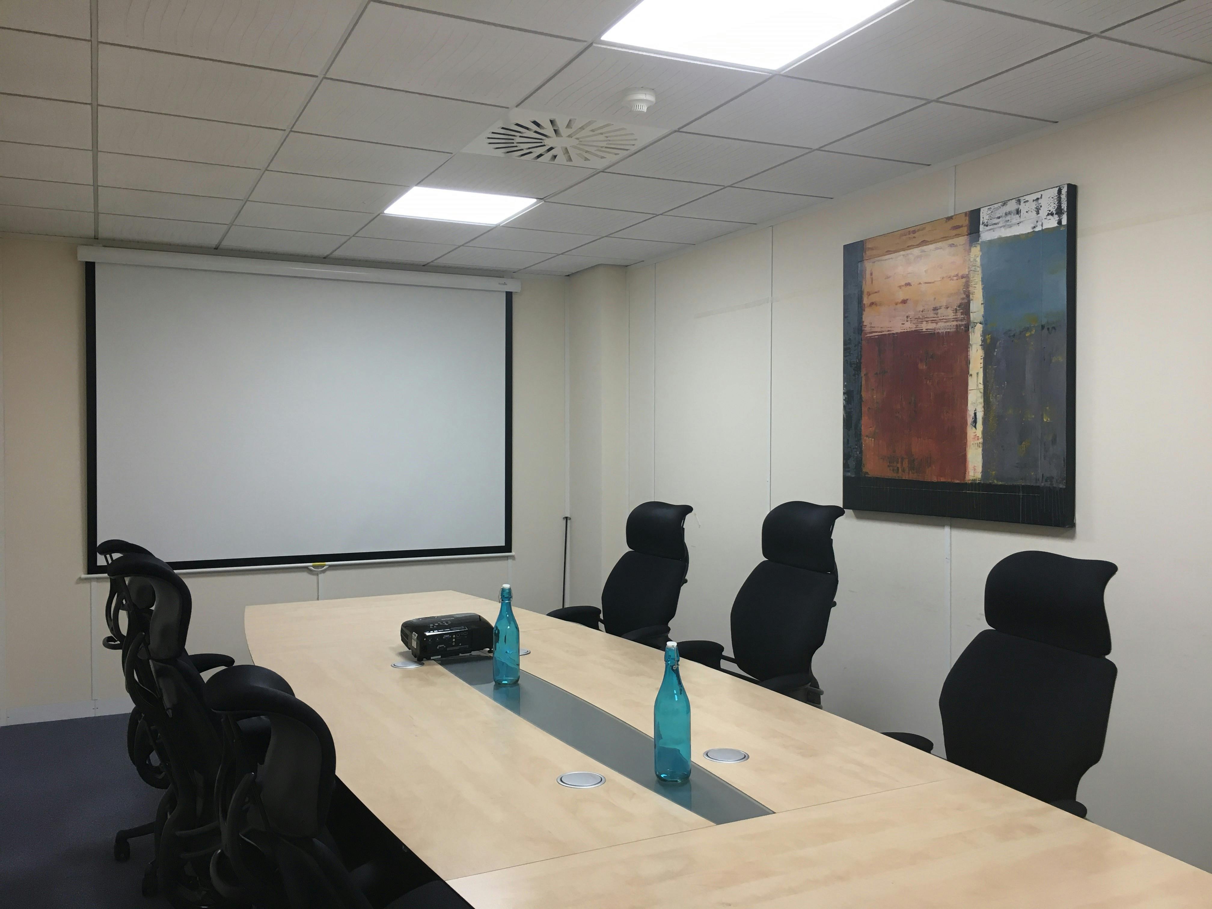 Modern meeting room in UBC Henley, featuring a long wooden table and ergonomic chairs.