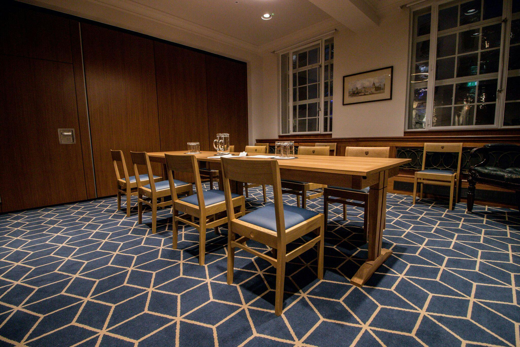 Meeting room with wooden table and geometric carpet for professional gatherings.