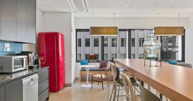 Modern 14-person meeting space with vibrant red fridge for networking and brainstorming.