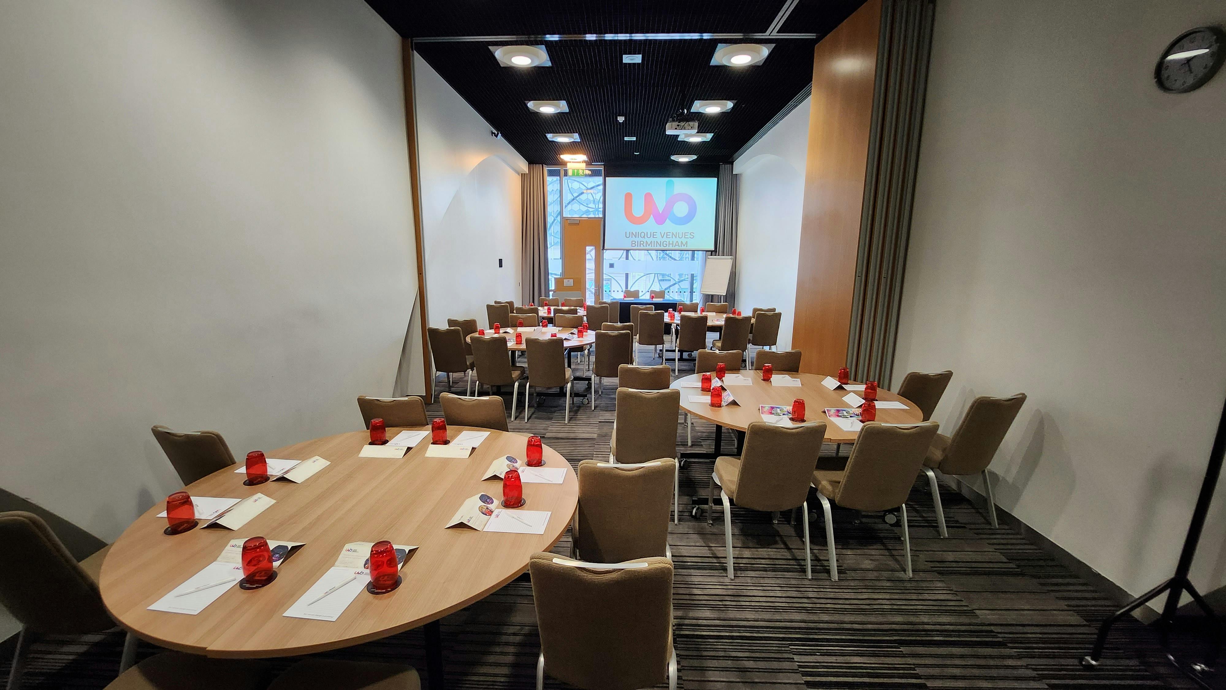 Meeting space in Birmingham with round tables and red candle holders for events.