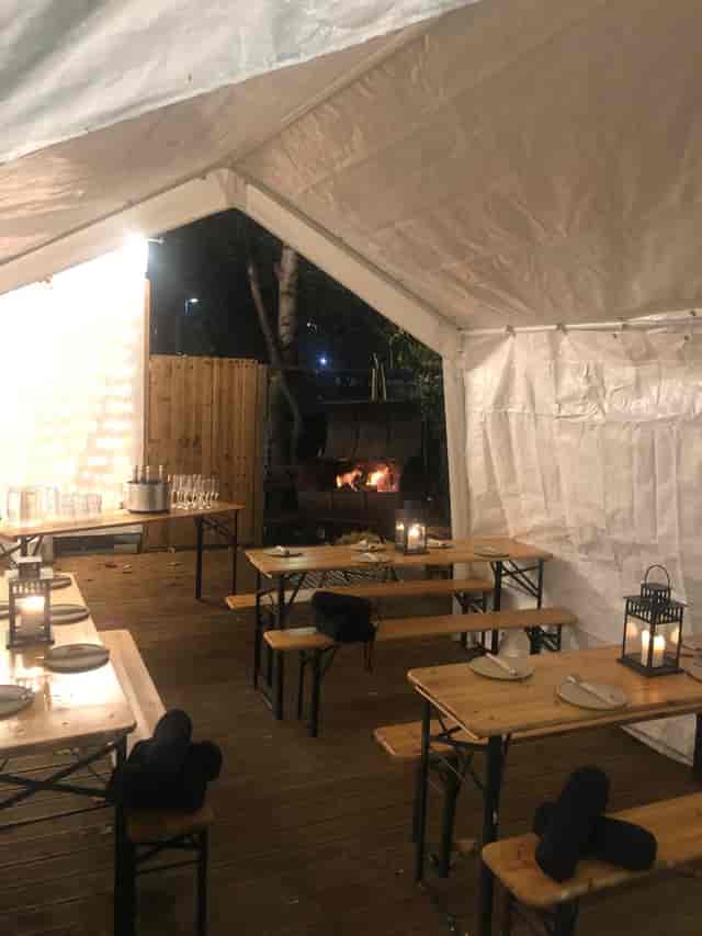 Cozy outdoor event space with tent, wooden benches, ideal for intimate gatherings.