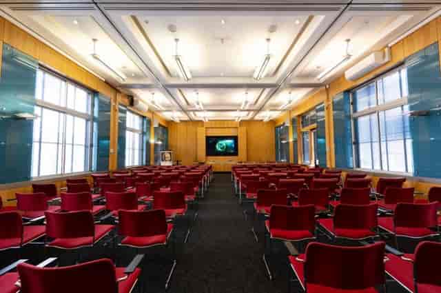 Council Chamber theater-style conference room with red seating for corporate presentations.