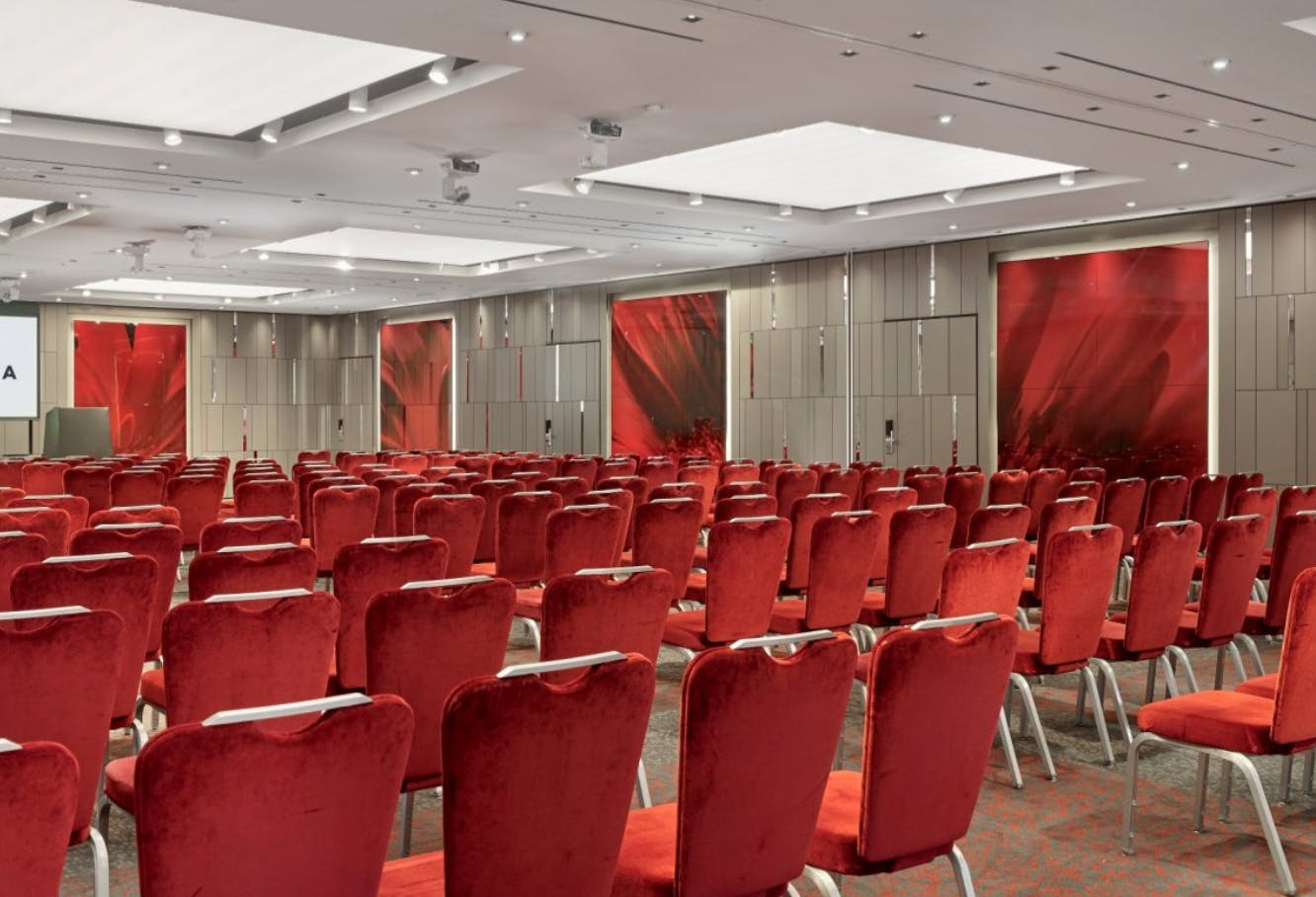 Ballroom at Park Plaza London Riverbank with plush red chairs for conferences and presentations.