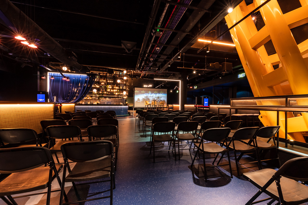 Corner Bar at TOCA Social: modern event space with black chairs for presentations and gatherings. - Banner