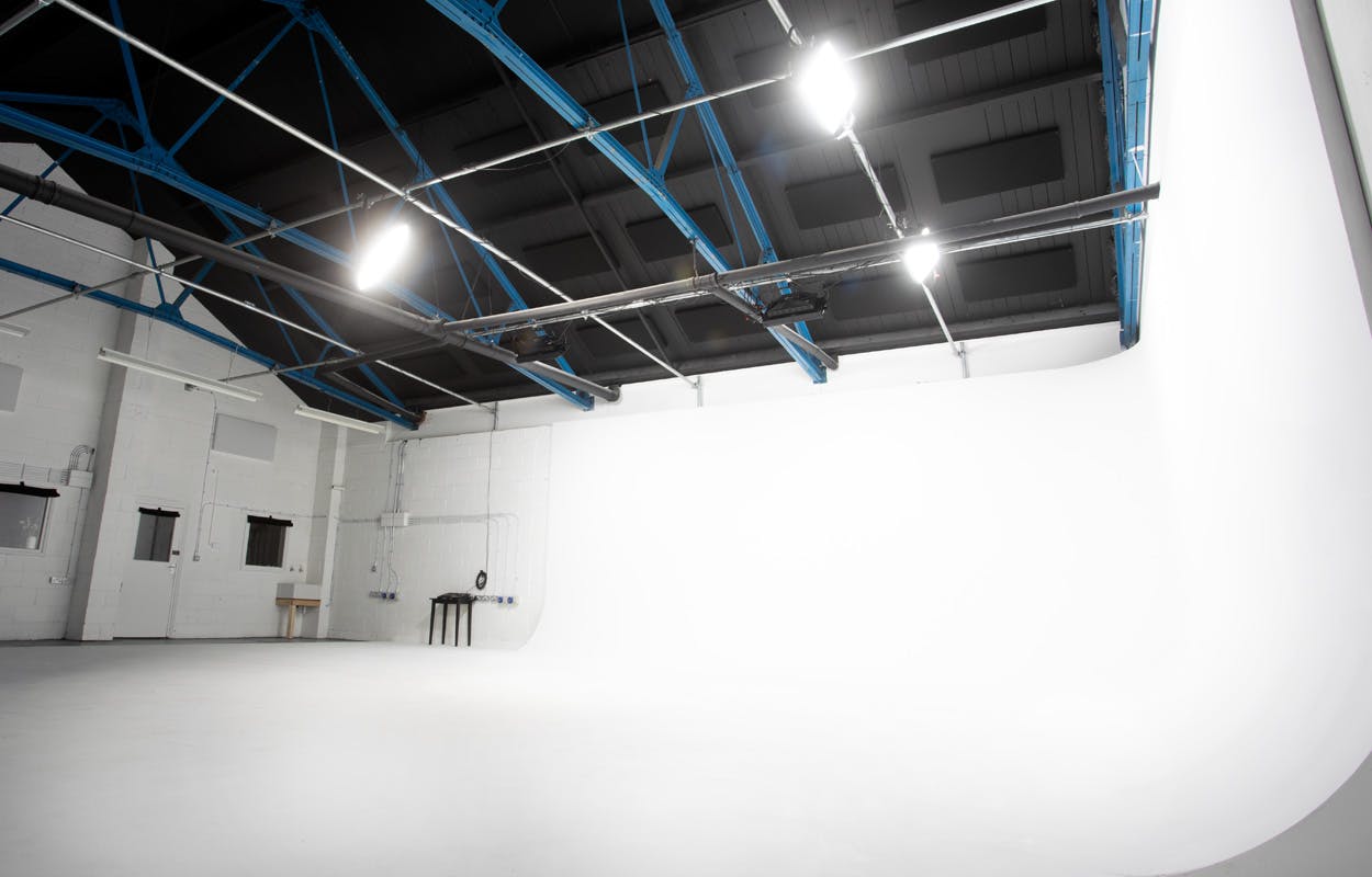 Versatile event space with white backdrop and high ceilings for corporate and creative events.