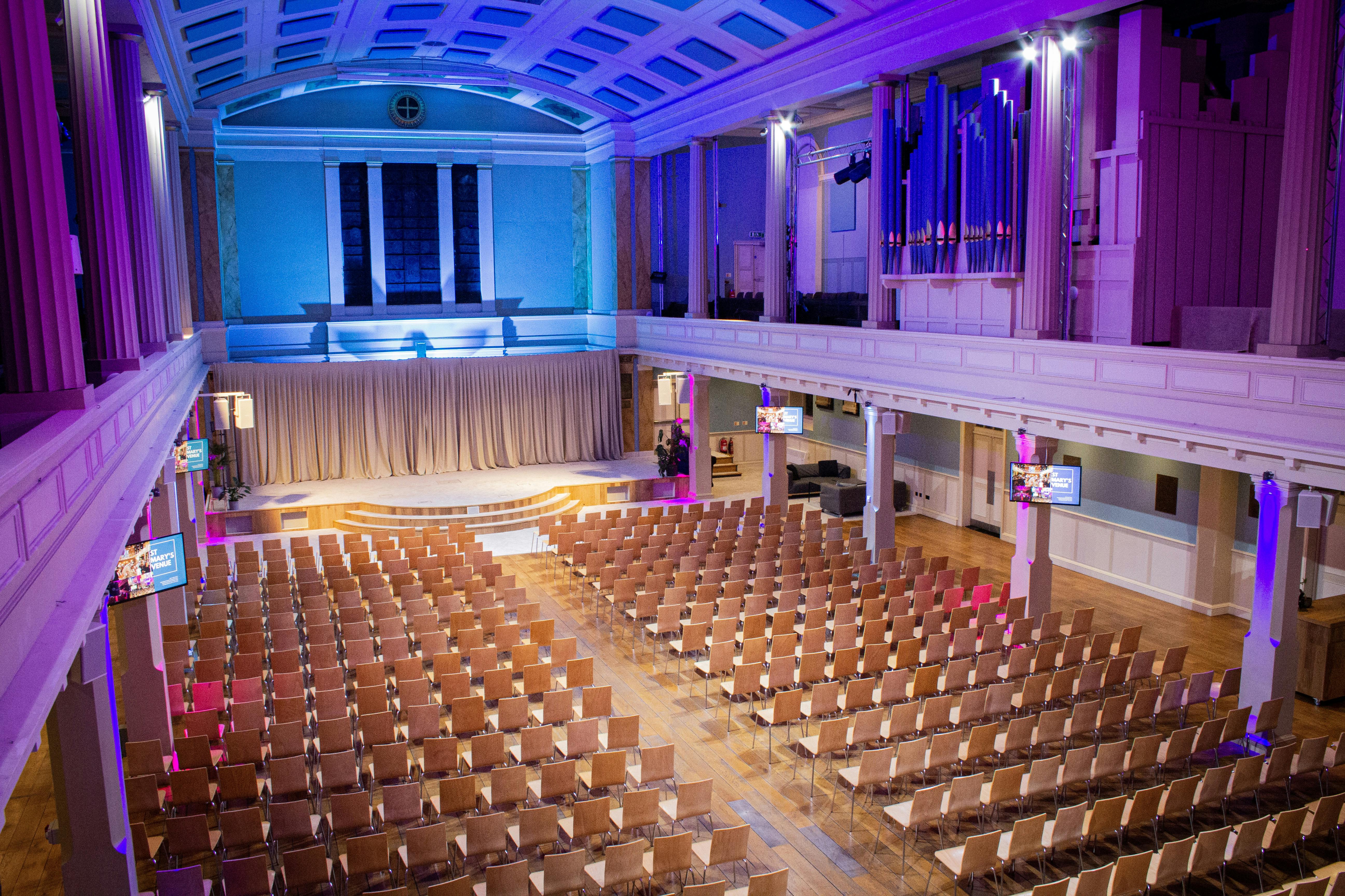 Spacious St Mary's Marylebone venue set for conferences with vibrant lighting and seating.