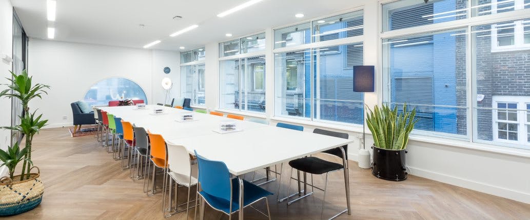 Modern meeting room with white table and colorful chairs for creative workshops.