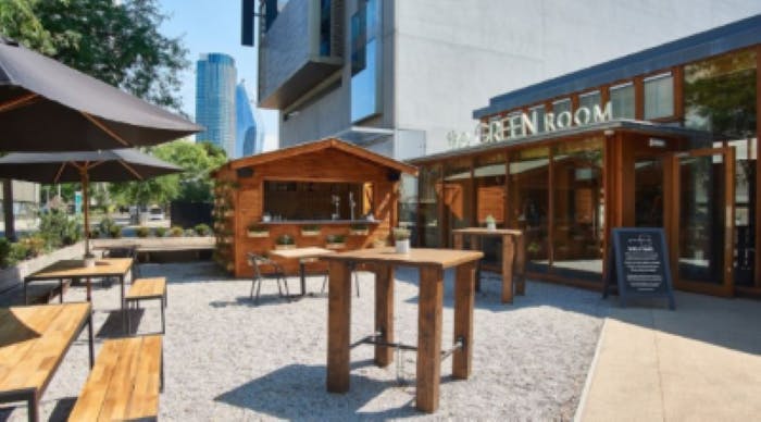 Outdoor bar with rustic furniture and city skyline, perfect for casual gatherings.