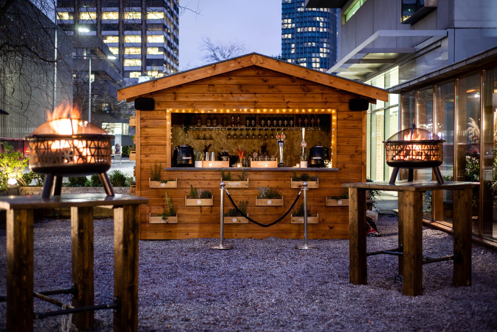 Stylish outdoor bar with fire pits, perfect for events and gatherings. - Banner