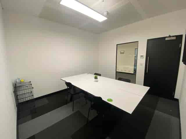 Minimalist meeting room at SPS2, featuring a white table and black chairs for brainstorming.