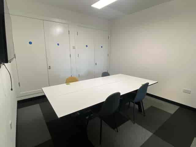 Minimalist meeting room with large white table, ideal for team meetings and presentations.